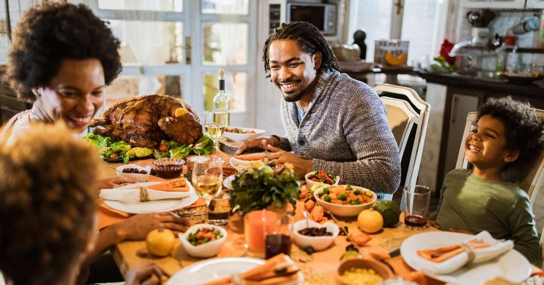 Familia feliz sentada alrededor de una mesa con una cena de Acción de Gracias.