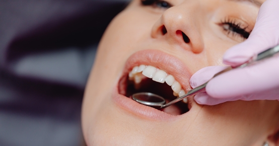 Close up of a dentist using a mirror tool inside a patient's open mouth