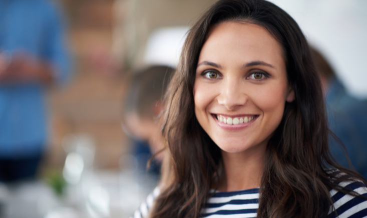 Smiling brunette woman in a striped shirt against a blurred background