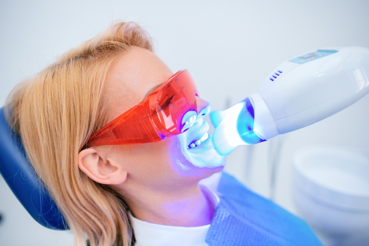 Dentist applying a whitening treatment to a patient using a blue UV curing light