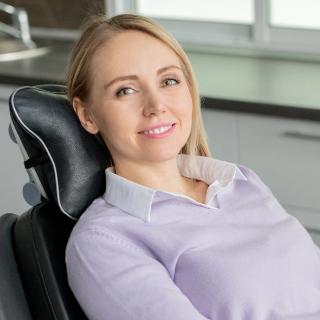 Smiling blonde woman in a lavender top seated in a dental chair