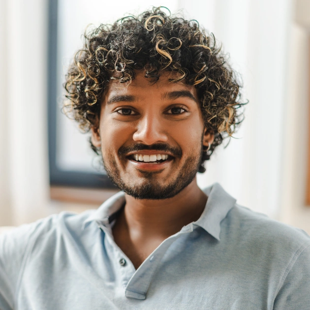 Portrait of a smiling young man with a beard against a light background