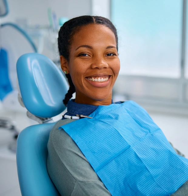 Smiling female patient in a blue scrub top seated in a dental chair