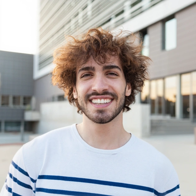 Portrait of a smiling young man with curly hair in a striped shirt