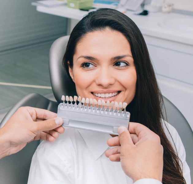 Dentist holding a tooth shade guide fan near a smiling female patient