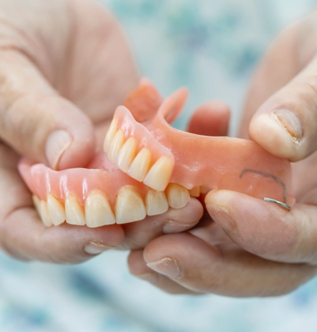 Dental professional holding a full set of upper dentures with both hands