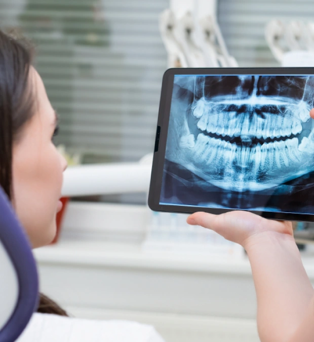 Dental professional reviewing a panoramic X ray on a tablet in a clinical setting