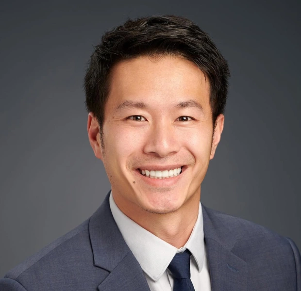 Portrait of Dr. David Wong smiling in a suit against a neutral background