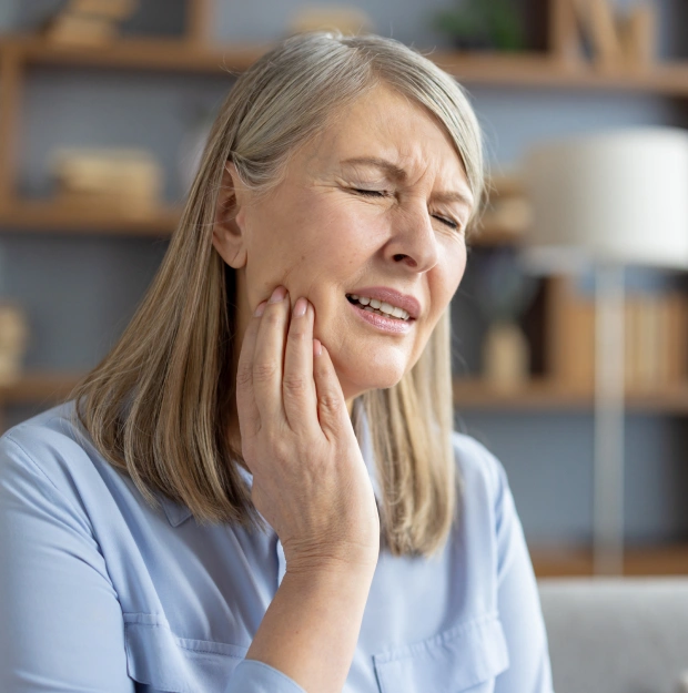 Older woman holding her cheek in pain with eyes closed