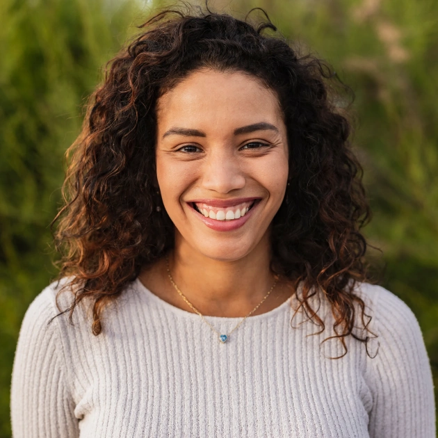 Portrait of a young woman with curly hair smiling in a bright setting