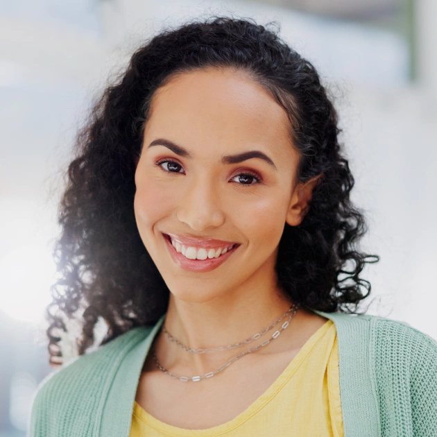 Portrait of a young woman with curly dark hair smiling outdoors