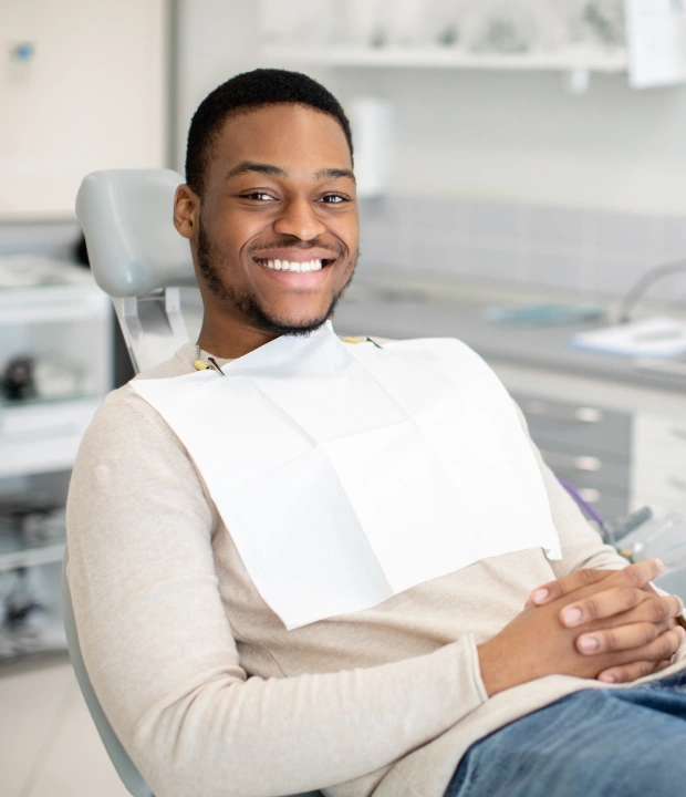 Young man smiling while seated in a dental chair during an appointment