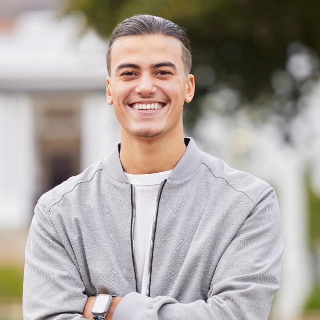 Retrato de un joven con los brazos cruzados sonriendo en un ambiente informal.