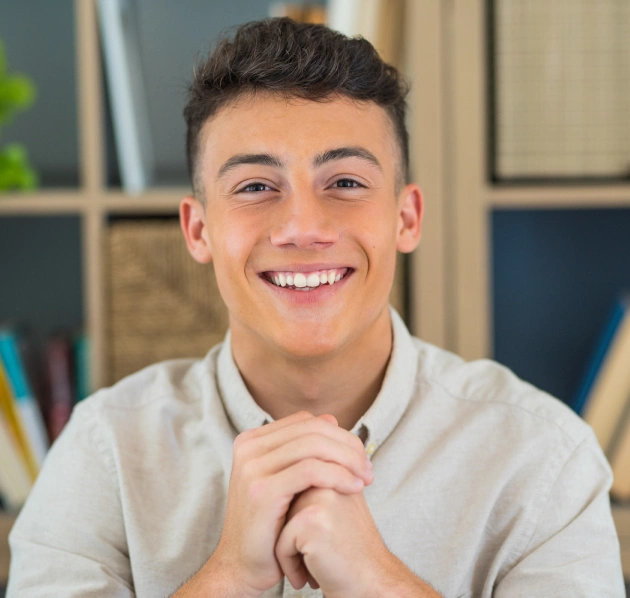 Portrait of a smiling young man with his hands clasped together