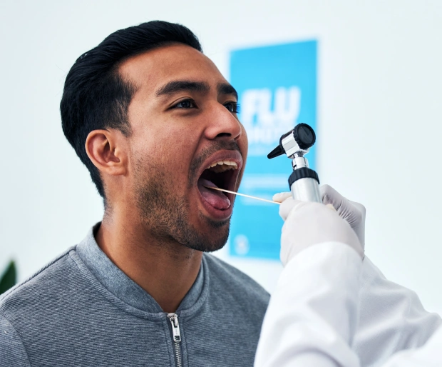 Male patient with his mouth open while a dentist uses a light tool during an exam