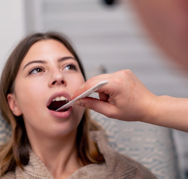 Dentist examining a female patient's mouth with a tool during an appointment