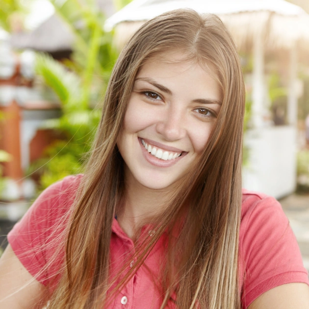 Young woman in a pink top smiling warmly in a bright indoor setting