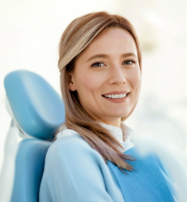 Female patient smiling while seated in a dental chair during a checkup