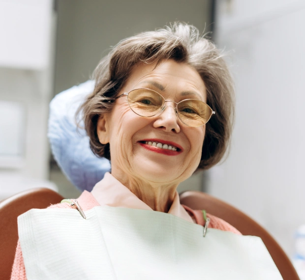 Portrait of an older woman in a dental bib smiling during an appointment