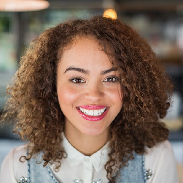 Portrait of a young woman with curly hair smiling in a casual setting