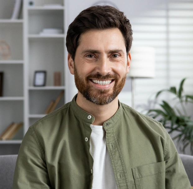 Smiling young man looking at the camera in a casual indoor setting
