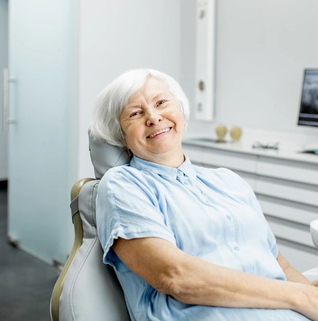Older woman smiling and relaxing in a dental chair during an appointment