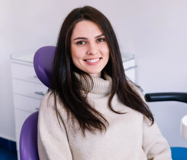 Portrait of a young woman with long dark hair smiling against a purple background