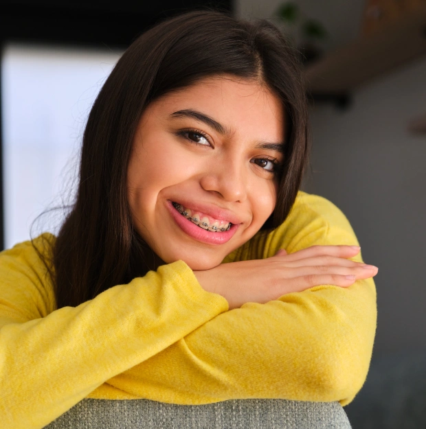 Young woman in a yellow top smiling with her arms crossed