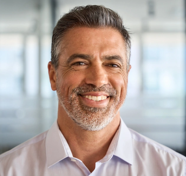 Portrait of a smiling middle aged man with grey hair and beard in a professional setting