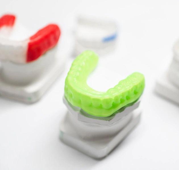 Red and green sports mouthguards displayed with their protective cases on a white background