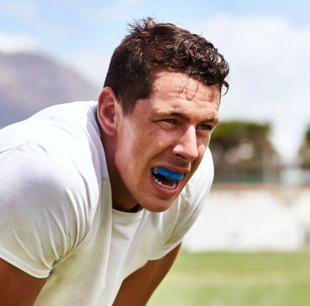 Male athlete wearing a blue sports mouthguard during an outdoor activity
