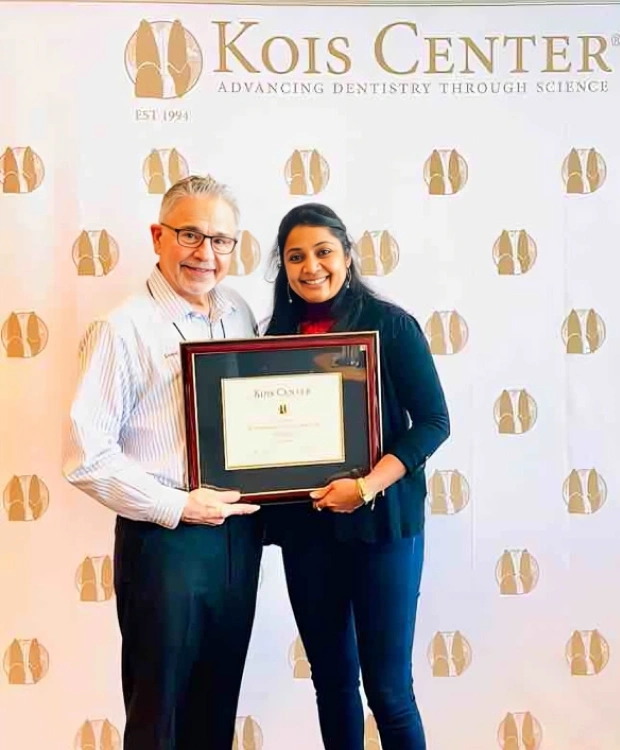Two people posing together holding a framed certificate