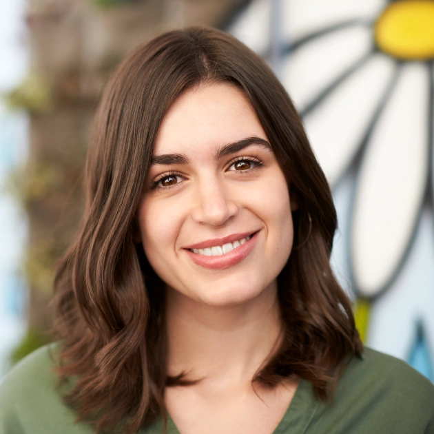 Portrait of a young woman with dark hair smiling outdoors