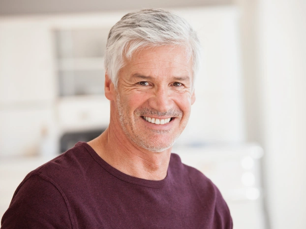 Portrait of a smiling middle aged man with silver hair against a light background