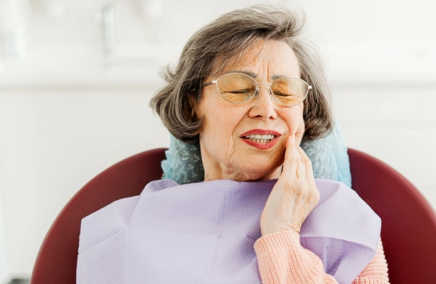 Older woman holding her cheek in discomfort