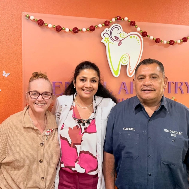 Dental Artistry Irving staff posing with patients in front of the office sign