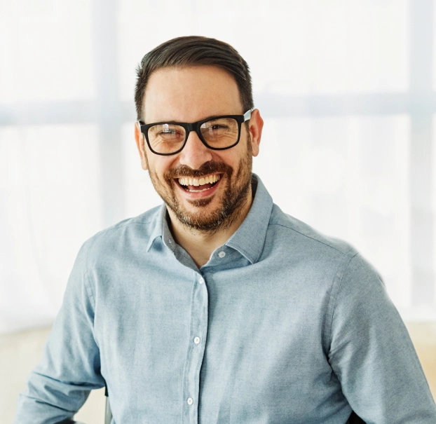Portrait of a smiling man with glasses in a blue shirt indoors