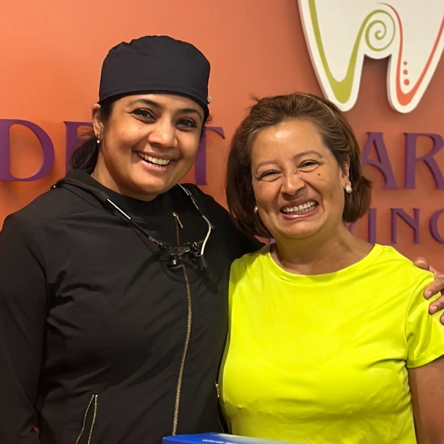 Dr. Radhika Srikrishnan Iyer posing with a patient in front of the Dental Artistry Irving sign