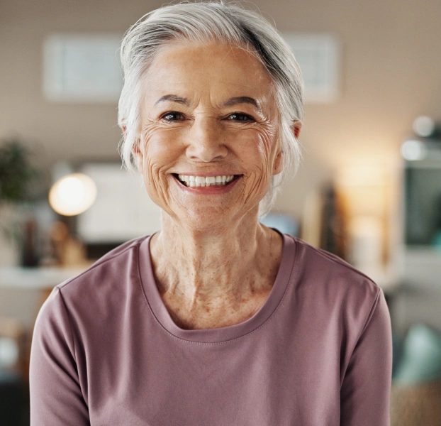 Portrait of a smiling older woman with short silver hair in a casual top