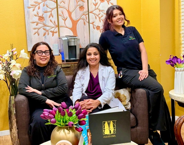 Dr. Radhika Srikrishnan Iyer and two Dental Artistry Irving staff members posing together in the office waiting room