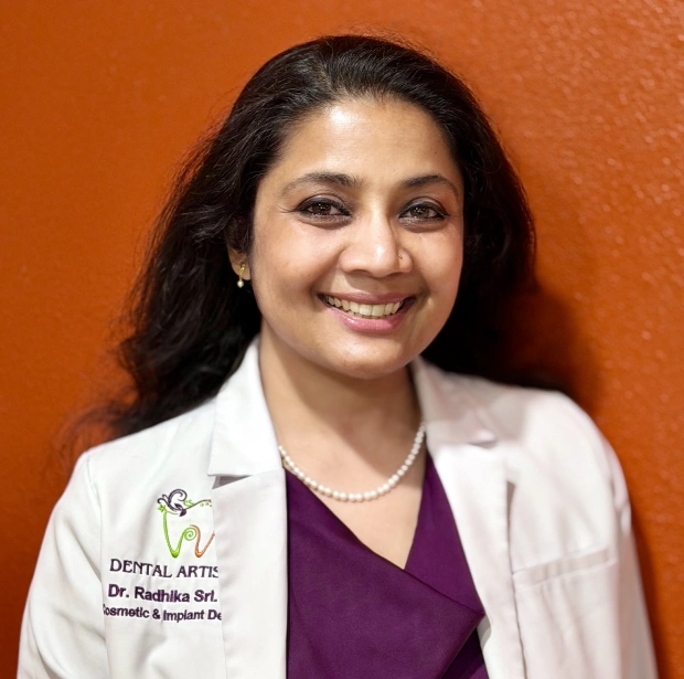 Dr. Radhika Srikrishnan Iyer smiling in her white coat at Dental Artistry Irving