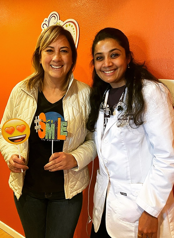 Dr. Radhika Srikrishnan Iyer and a patient holding smile emoji signs at Dental Artistry Irving