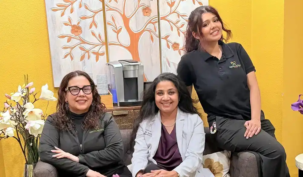 Dr. Radhika Srikrishnan Iyer and two Dental Artistry Irving staff members posing together in the office waiting room