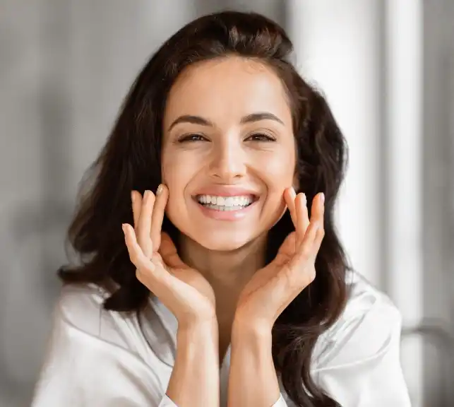 Portrait of a smiling young woman with her hands on her cheeks
