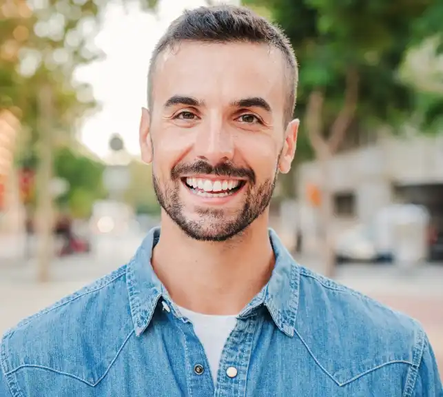 Portrait of a smiling man in a denim shirt in an outdoor setting