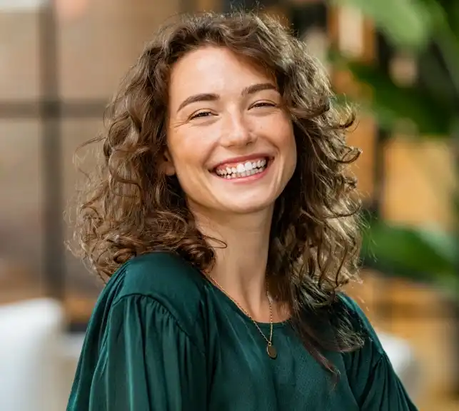 Portrait of a young woman with long wavy hair smiling outdoors