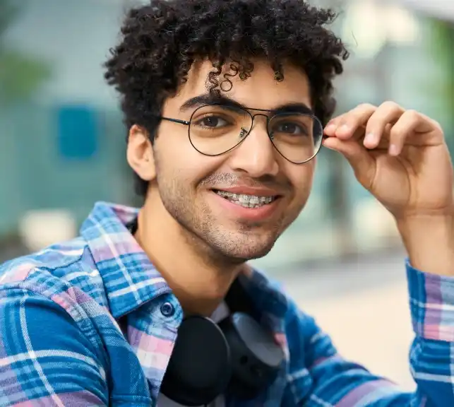 Young man with glasses and curly hair smiling