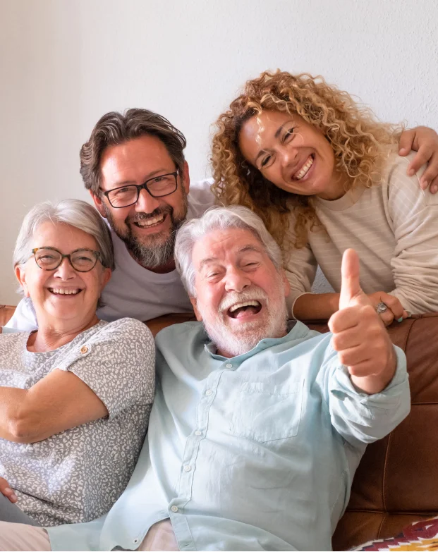 Happy multigenerational family, with three older adults and two younger adults smiling together.