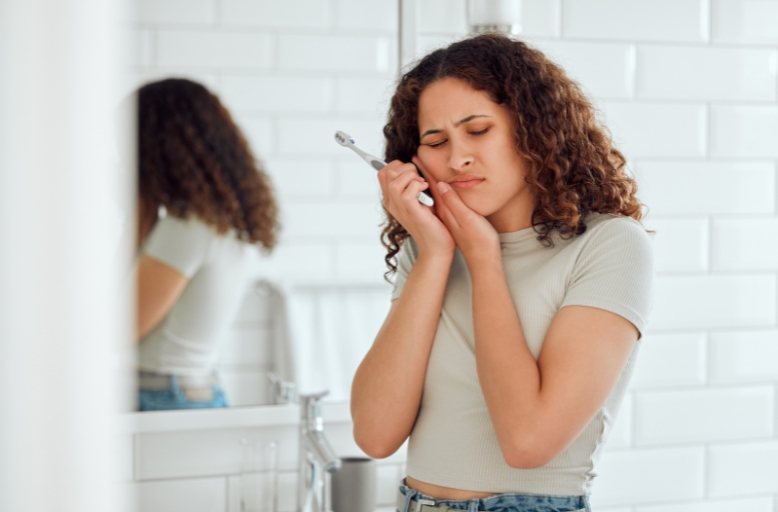 Woman holding cheek in pain after knocked out tooth demonstrating dental emergency and 60-minute rule for tooth avulsion treatment