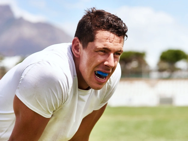 Male athlete wearing a blue custom sports mouth guard during outdoor activity near The Dentist Place of Clearwater in Clearwater, FL
